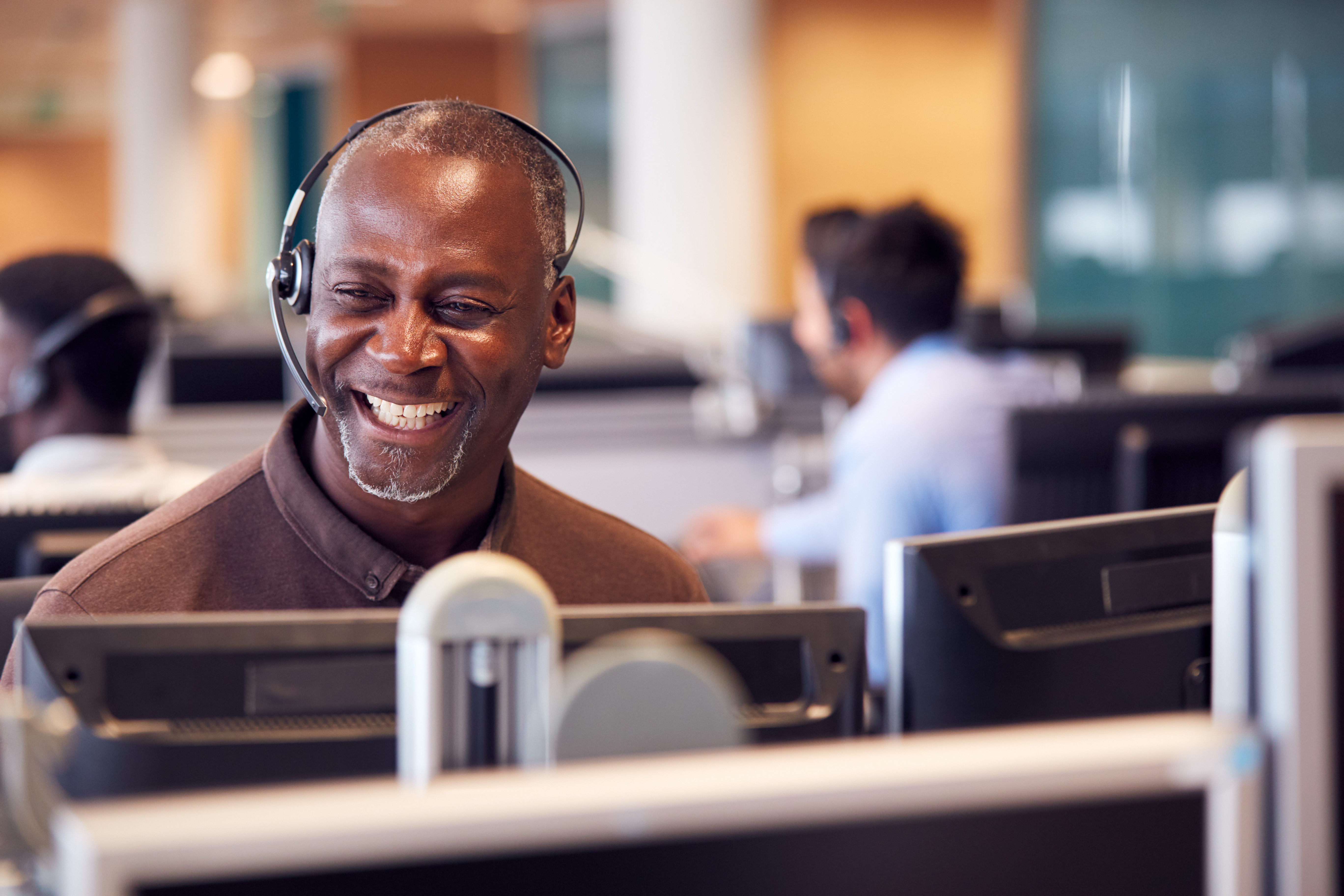A customer representative smiling on the phone.