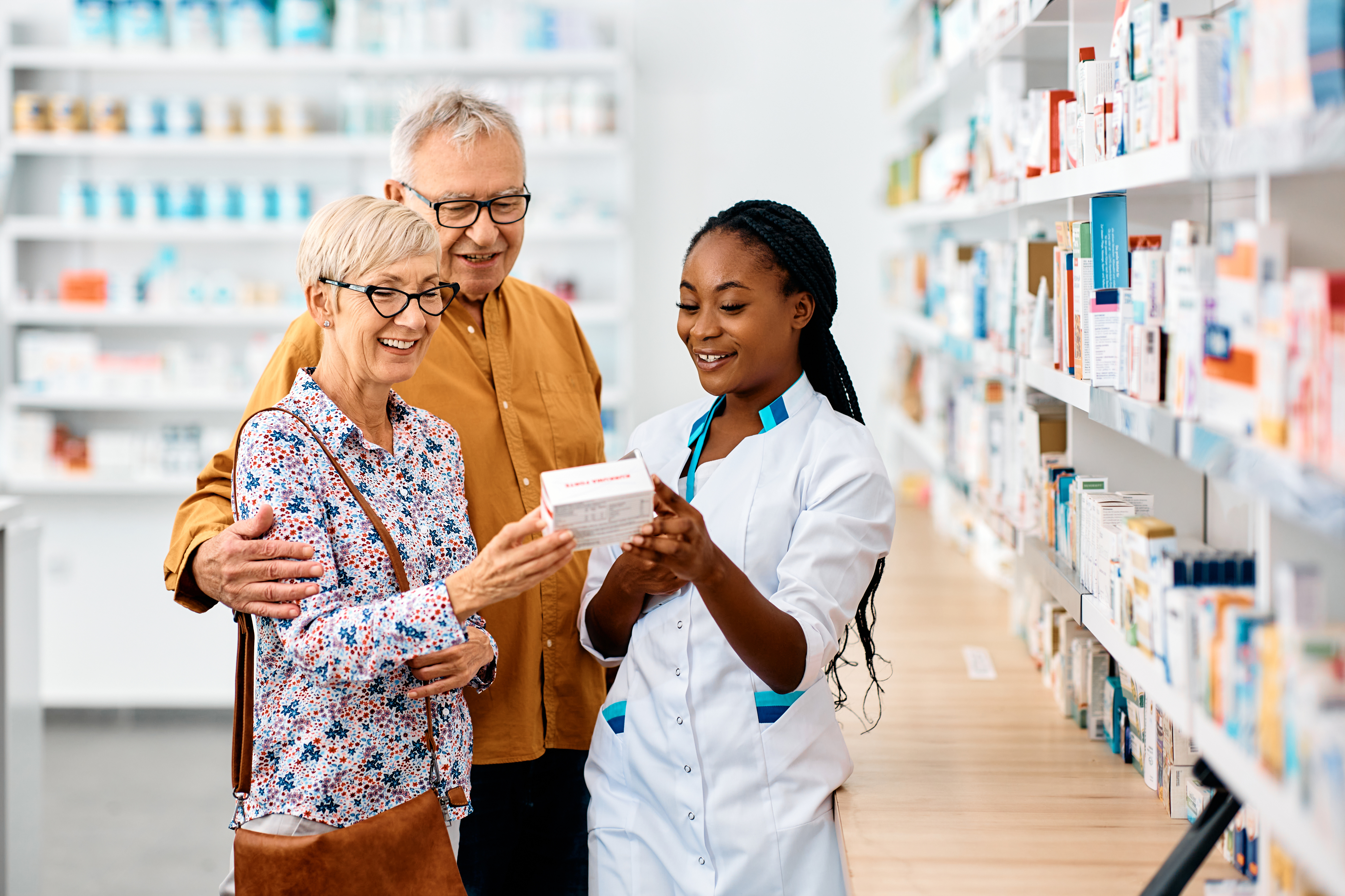 A pharmacist showing an older couple medicine.