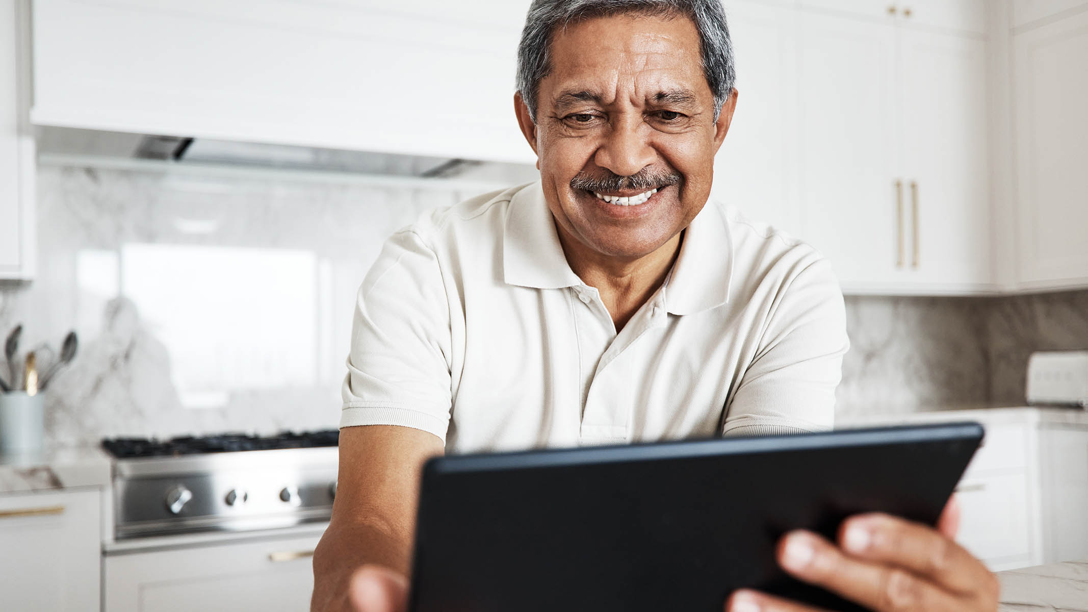 An older man reading looking at his laptop and smiling