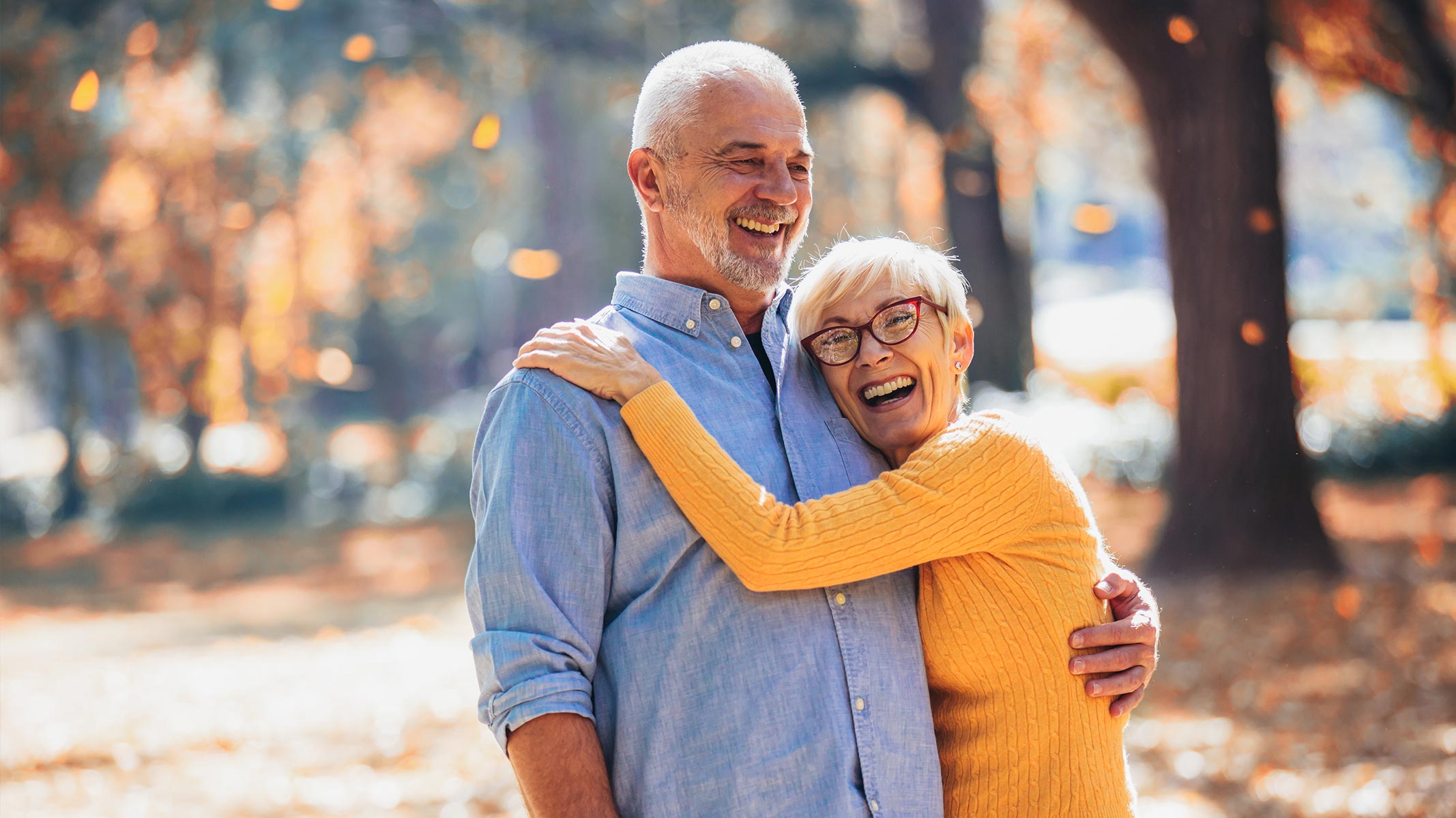 An older couple hugging and smiling outside